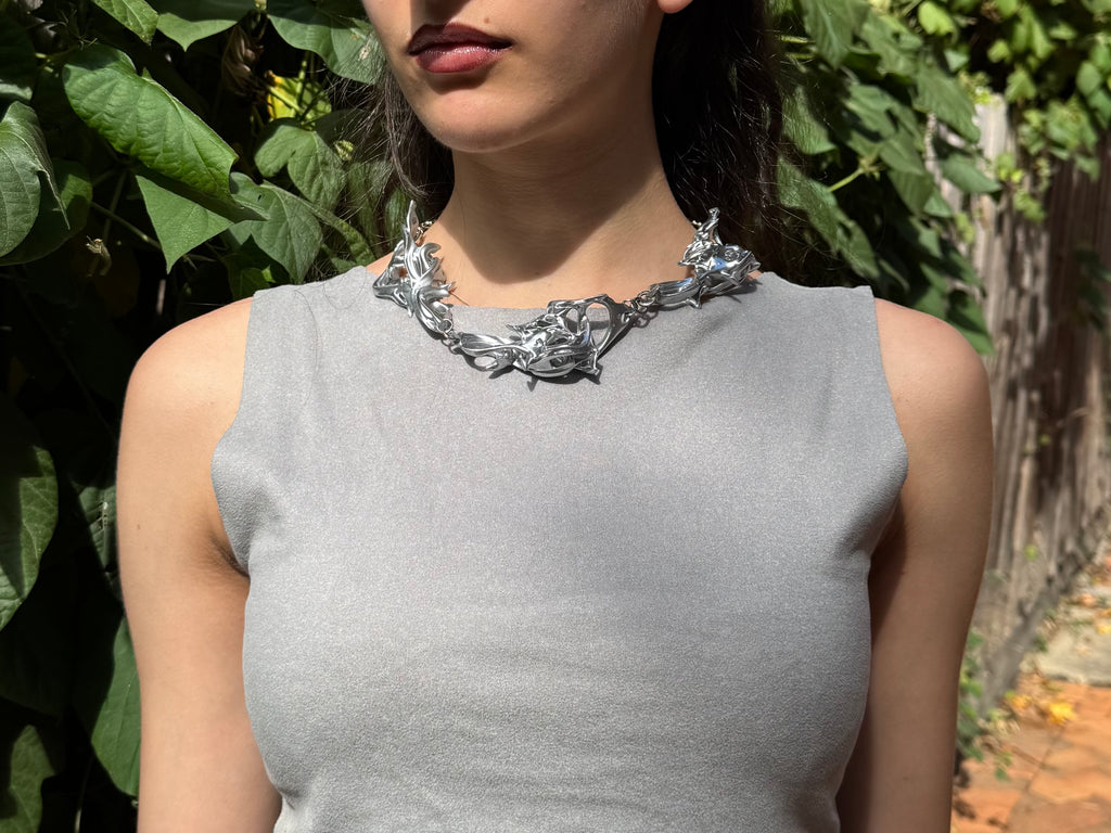 Woman wearing a silver statement 3D printed necklace.