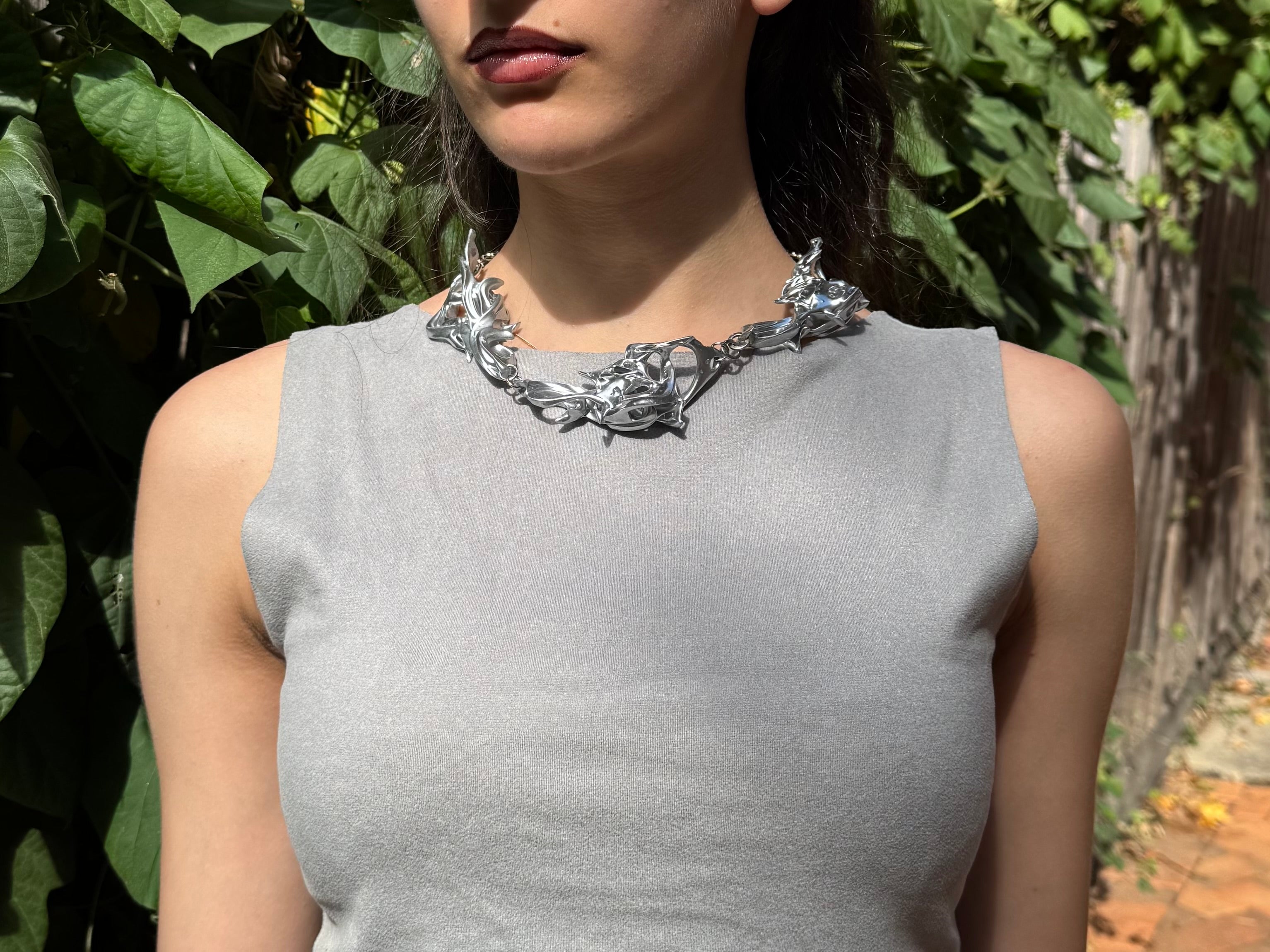 Woman wearing a silver statement 3D printed necklace.