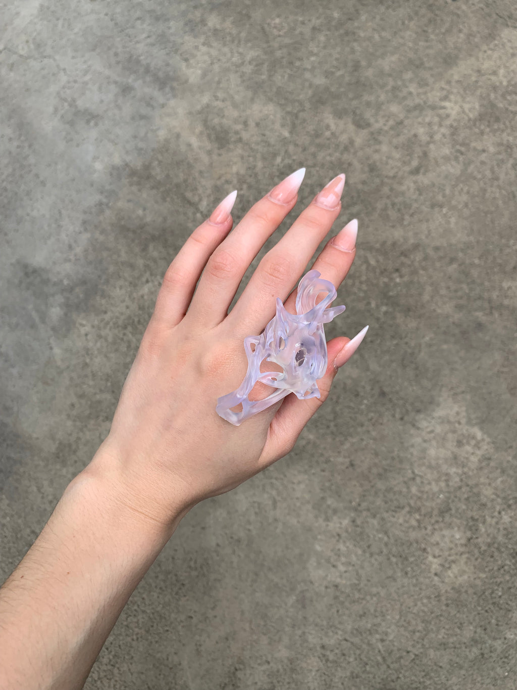 Hand wearing a clear resin statement 3D printed ring inspired by bones and fossils