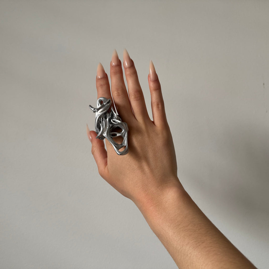 Hand wearing a unique silver ring on a plain background