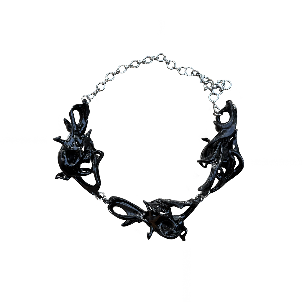 Black fossil inspired necklace on a white background