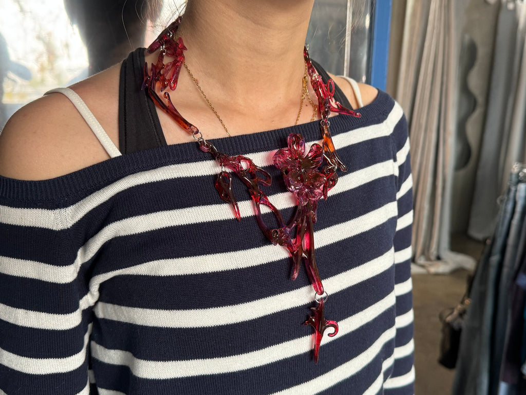 Person wearing a red floral statement chunky necklace