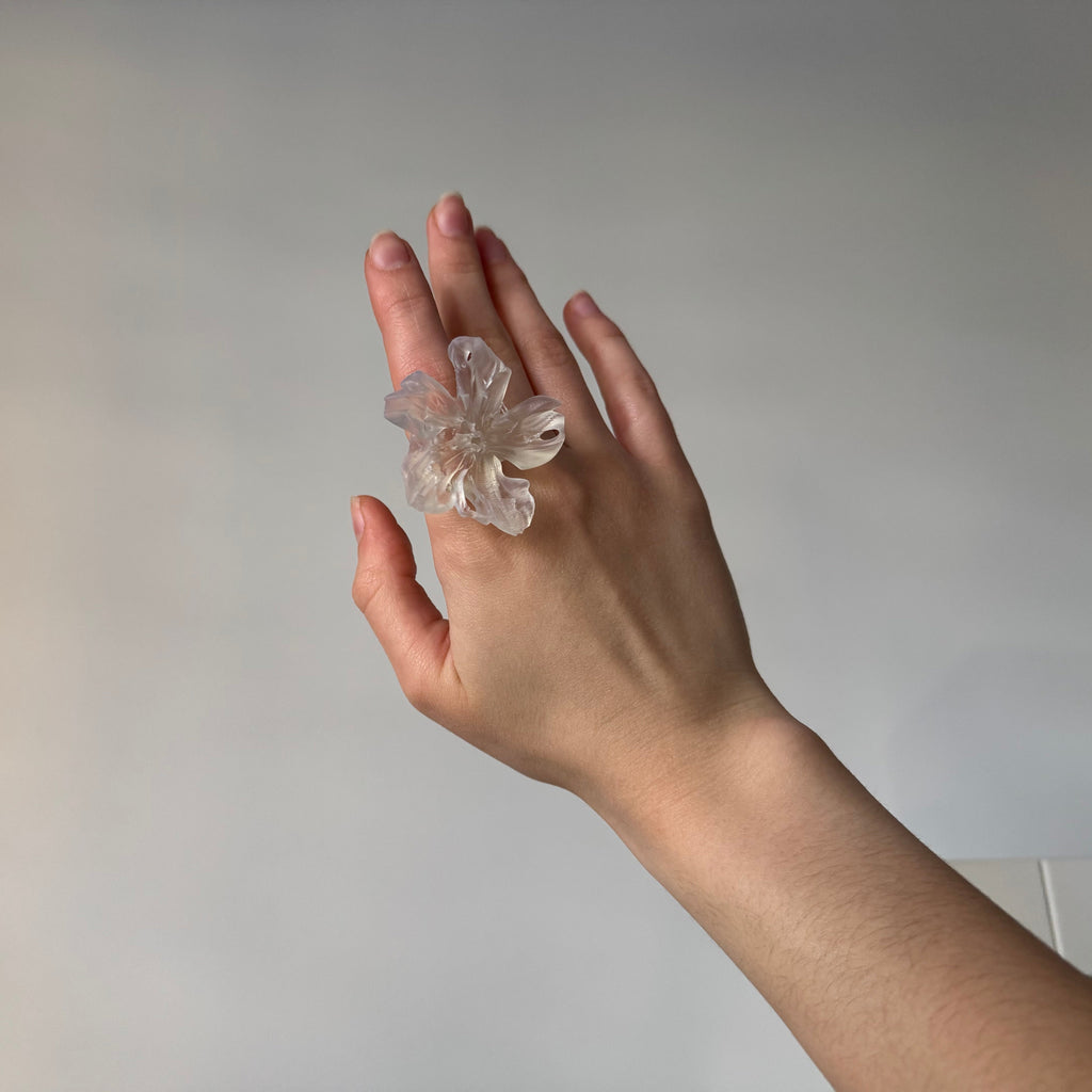 Abstract clear 3D printed resin flower ring worn on a hand.