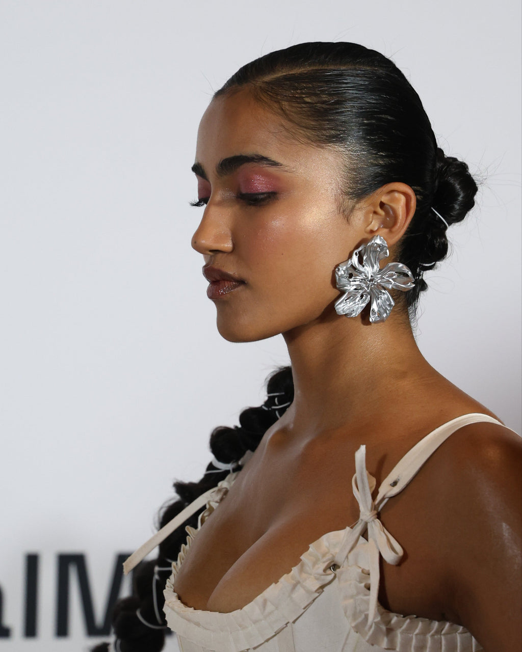 Woman styled with large resin 3D printed statement silver flower earrings. 