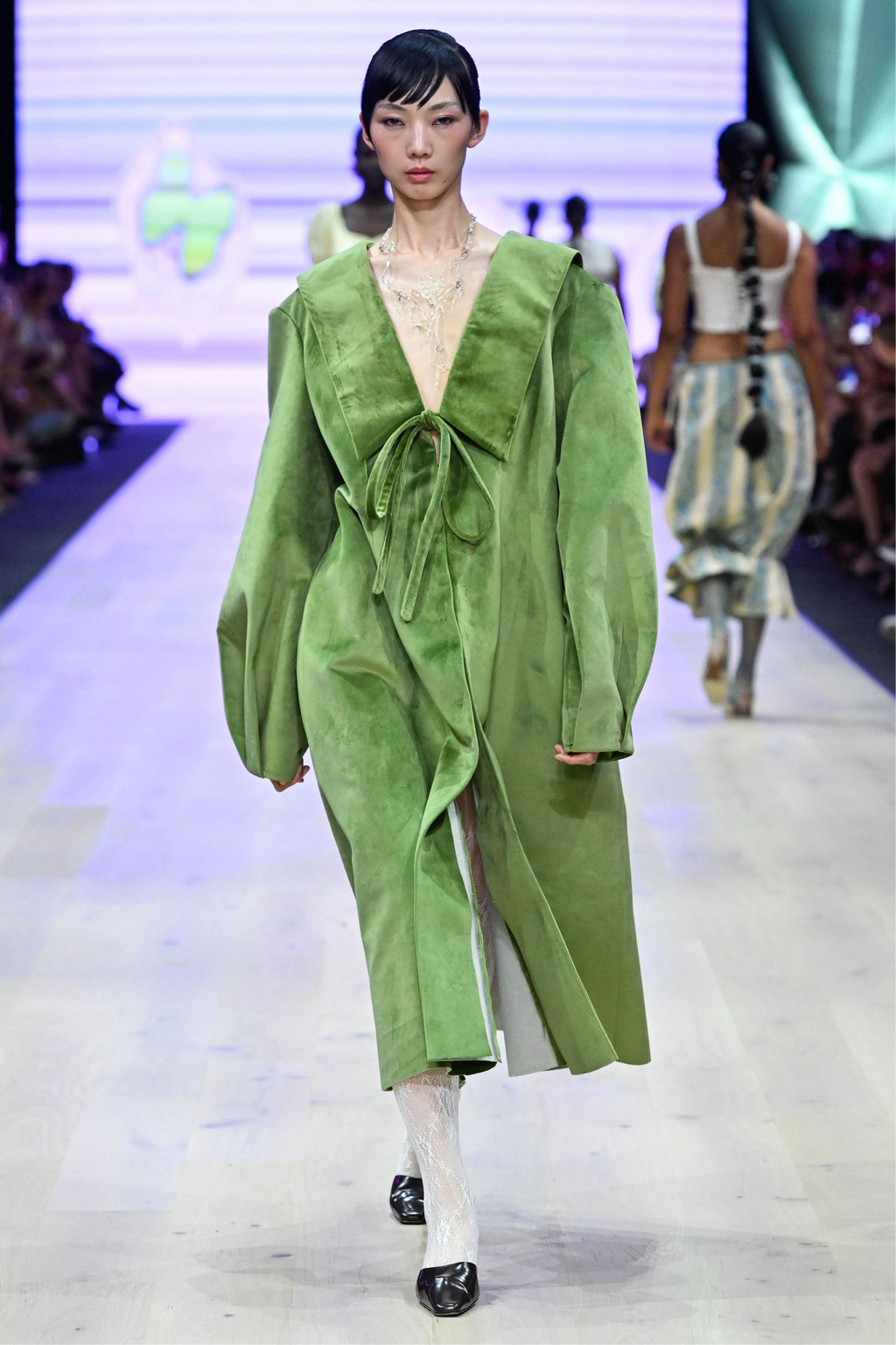 Model wearing statement clear gloss necklace on a runway