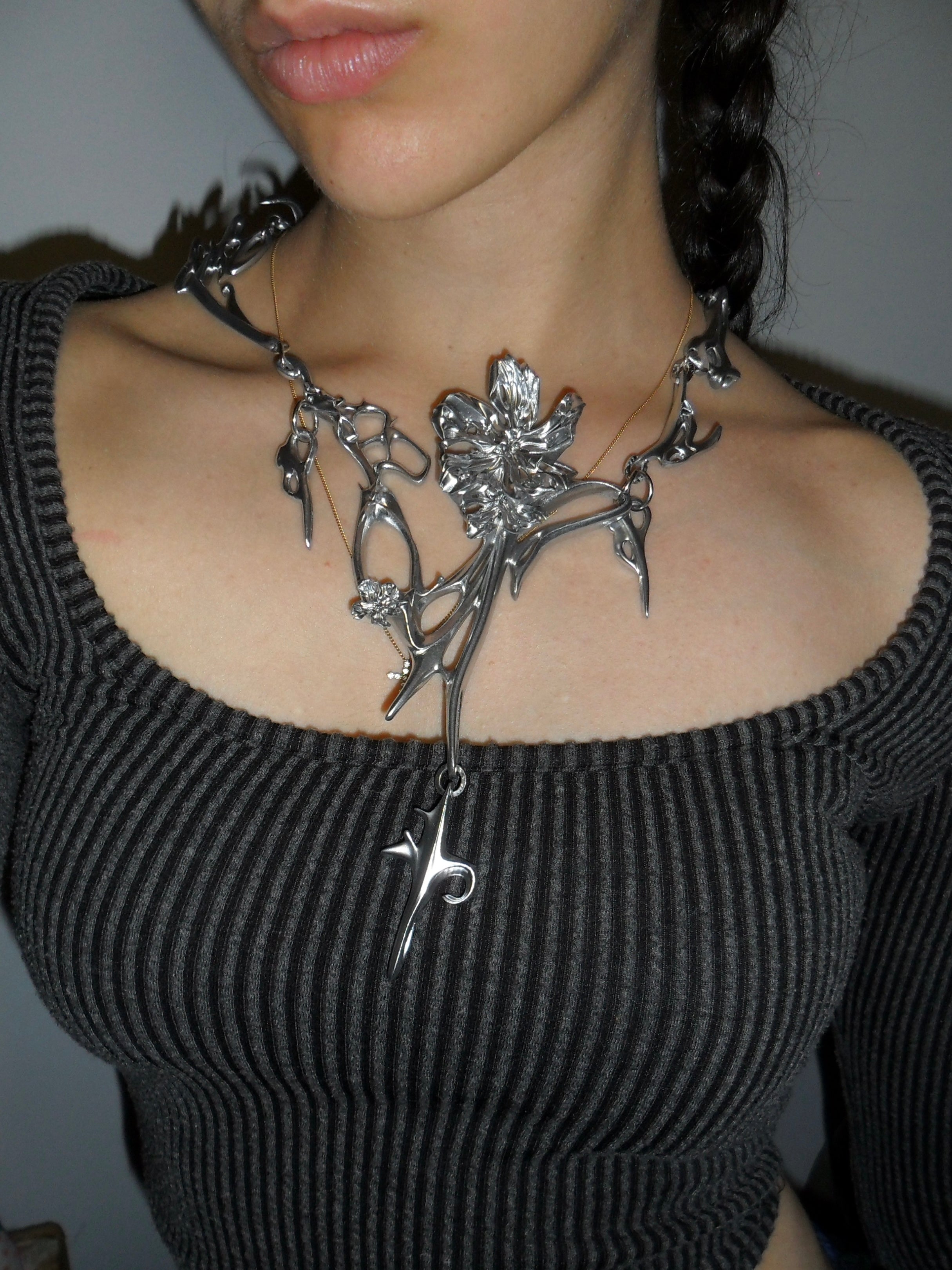 Silver necklace with floral design worn by a person.