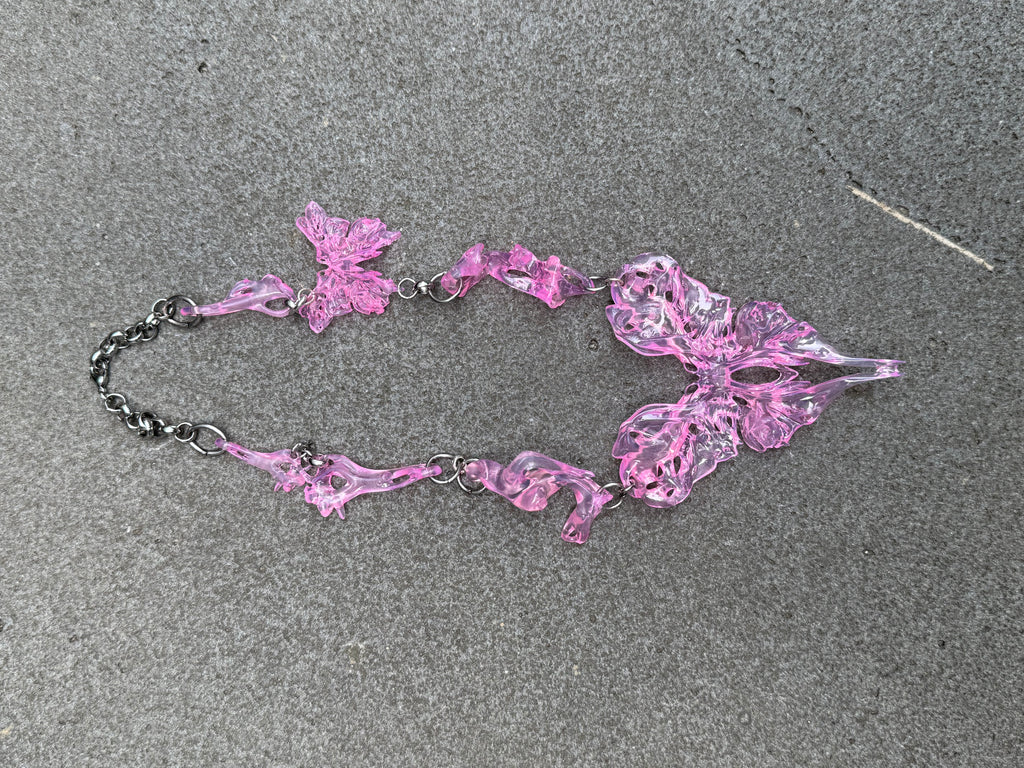 Pink heart butterfly abstract necklace on a gray surface