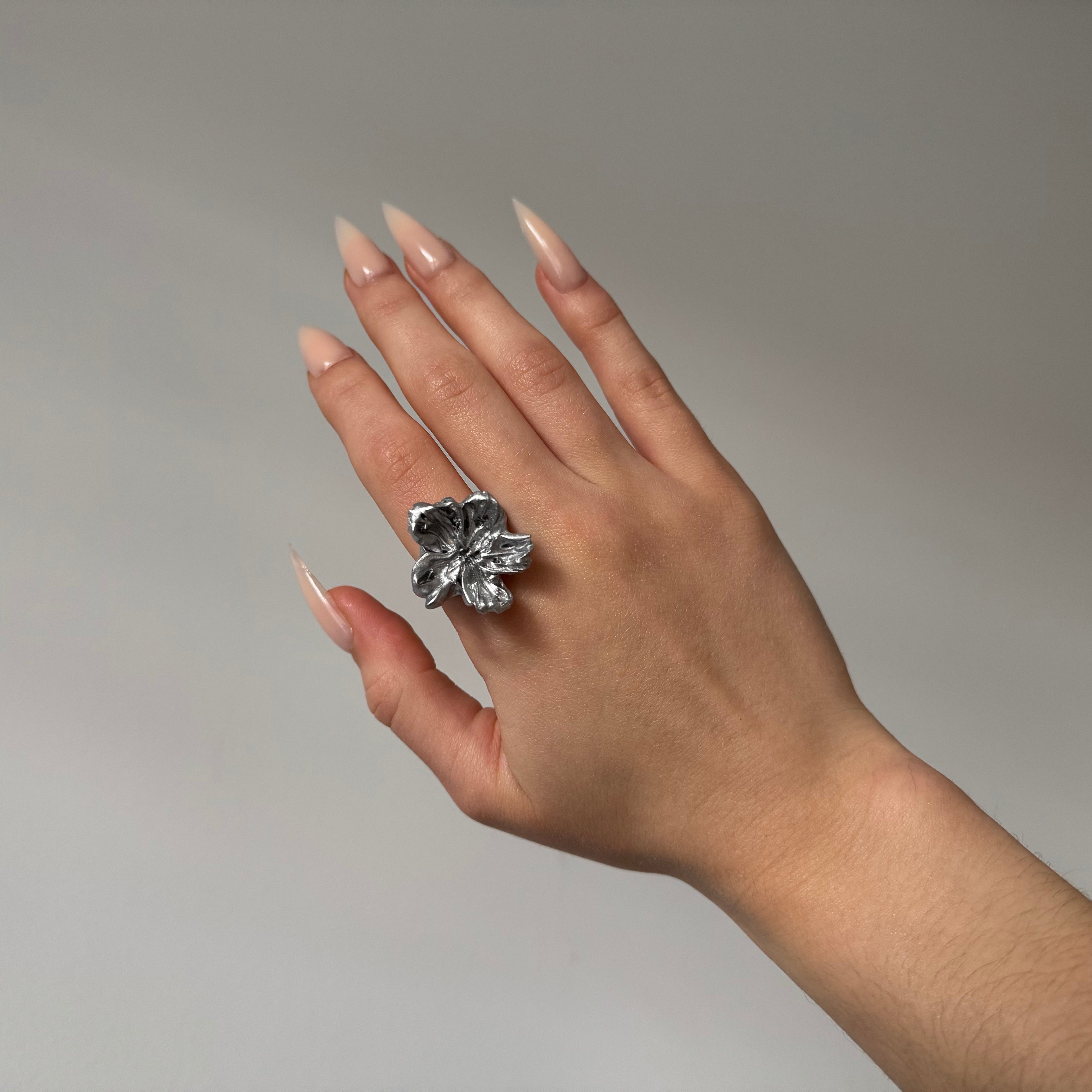 Hand wearing a small 3D printed flower silver ring
