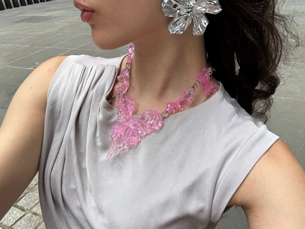 Woman wearing a pink statement heart necklace and silver earrings