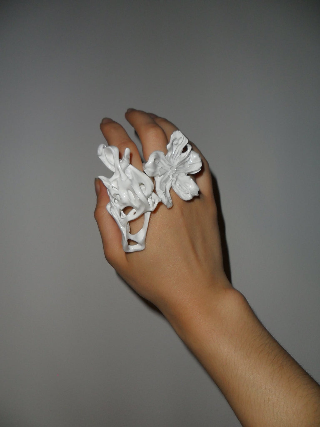 Hand wearing white 3D printed bone-fossil like inspired resin ring