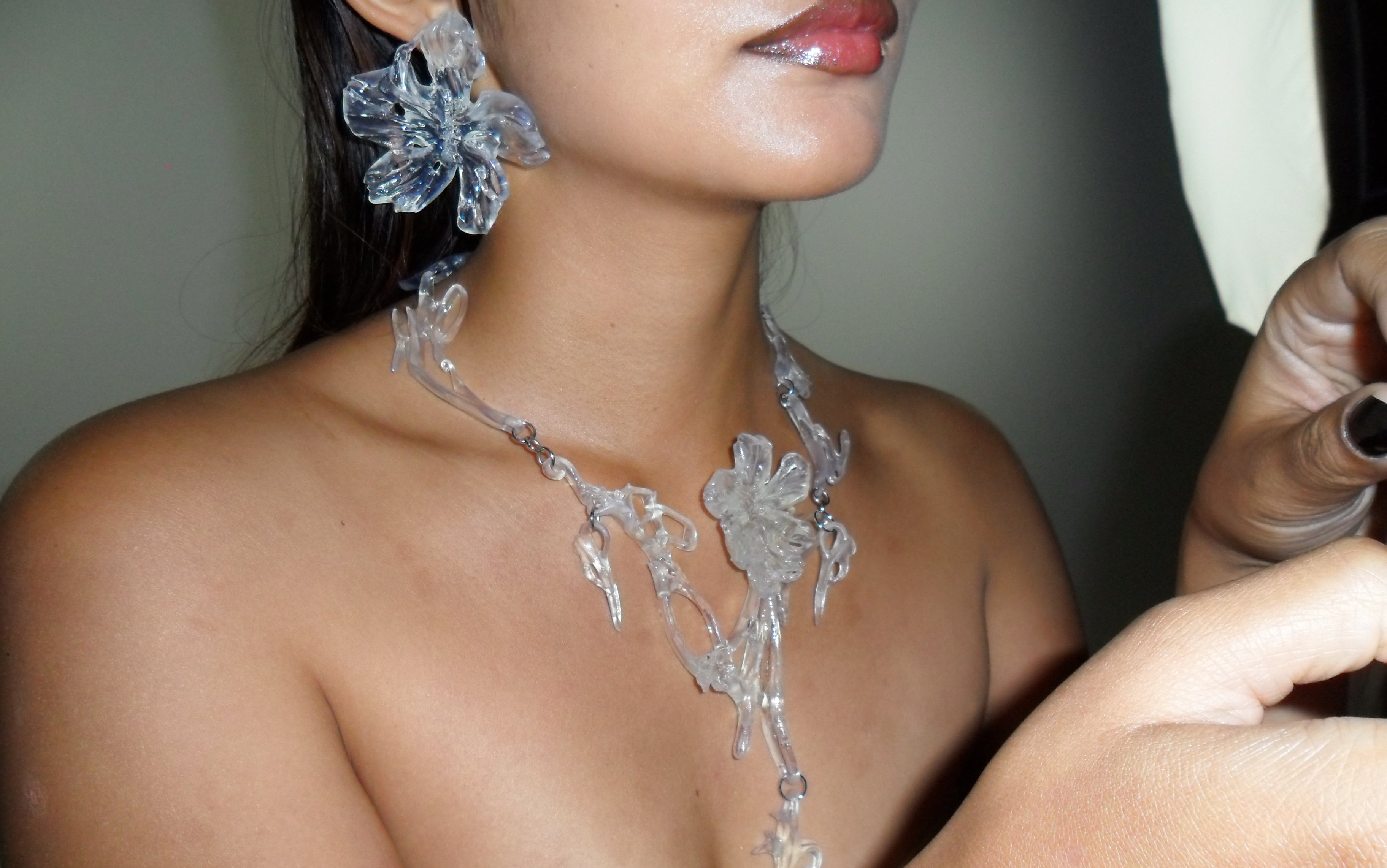 Close-up of a woman wearing a floral necklace and earrings in a clear gloss resin finish.